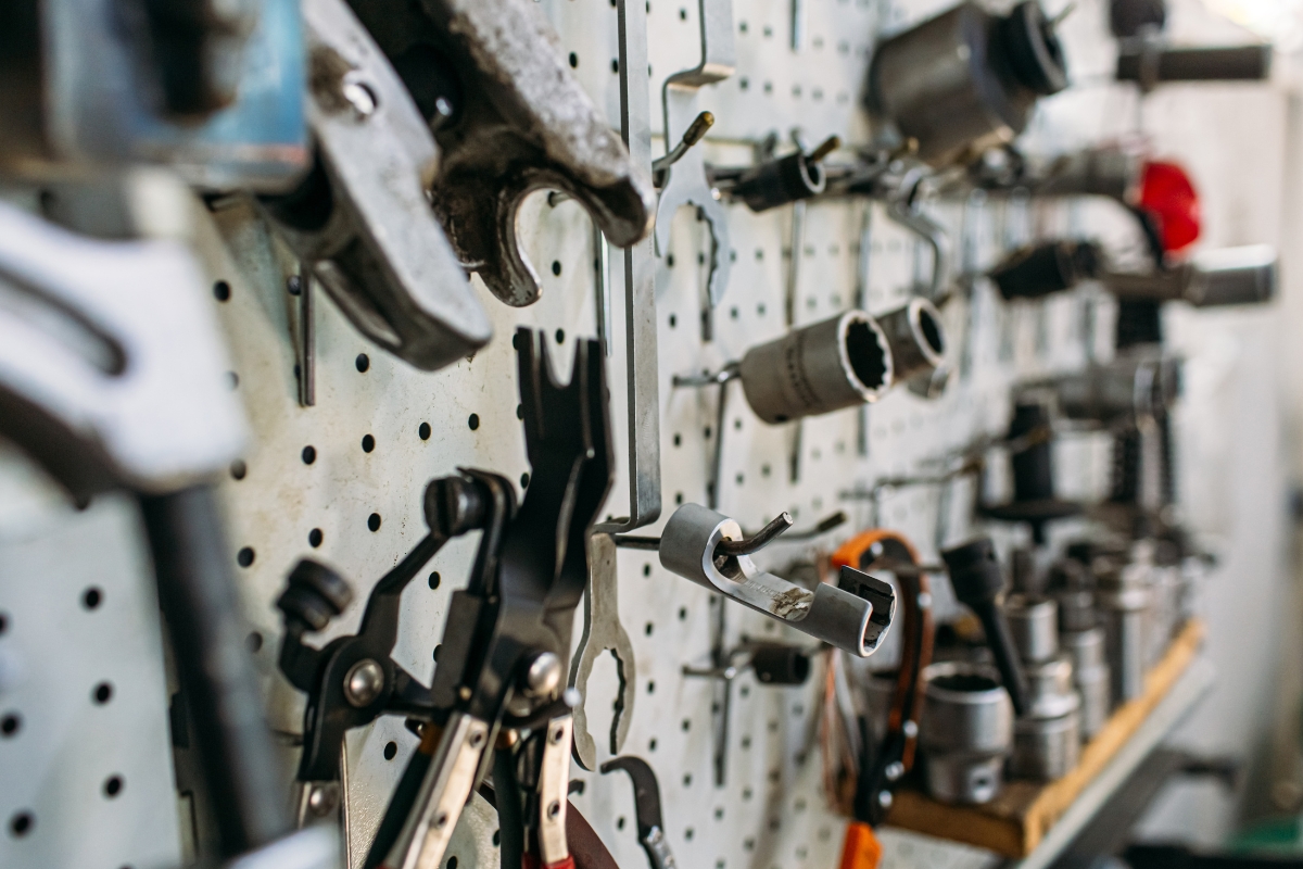 Close-up of various repair tools, including wrenches and pliers, organized on a workshop pegboard.